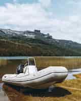 Foto gratuita ripresa verticale di una barca bianca parcheggiata nel lago con una montagna sullo sfondo