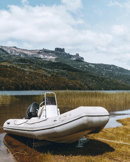 山を背景に湖に駐車した白いボートの垂直ショット