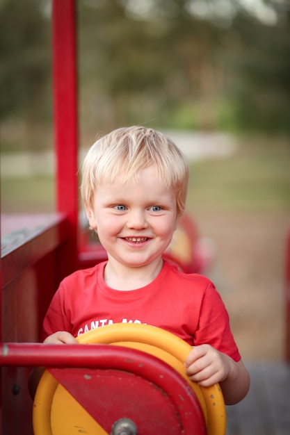 Vertical shot of a white Caucasian kid with blond hair holding the steering wheel