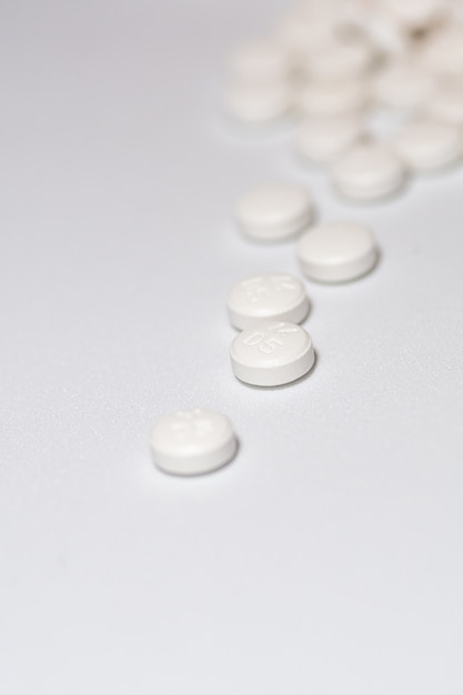 Вертикальный выброс белых круглых таблеток на белой поверхности