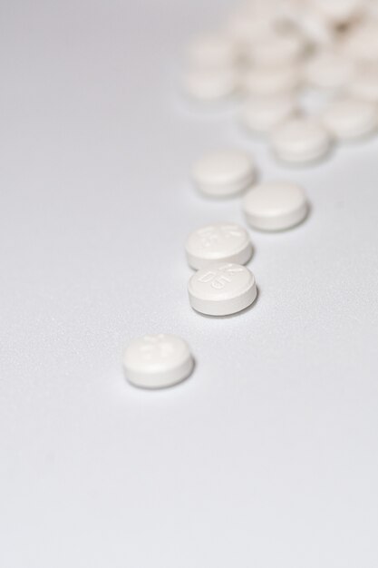 Vertical shot of white circular pills on a white surface