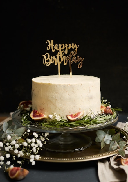 Вертикальный снимок белого торта мечты с днем рождения с зелеными листьями внизу