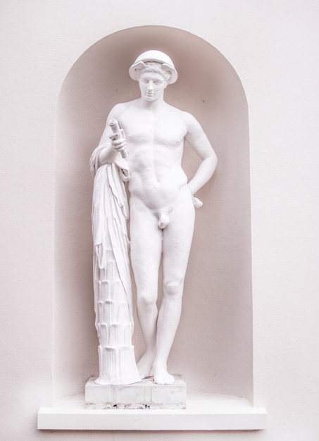 Foto gratuita colpo verticale di una scultura in pietra bianca di un maschio nudo