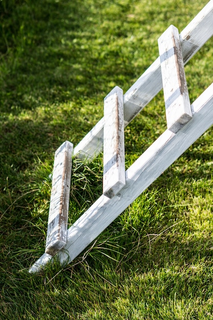 Free photo vertical shot of a white wooden ladder on the grass in the park