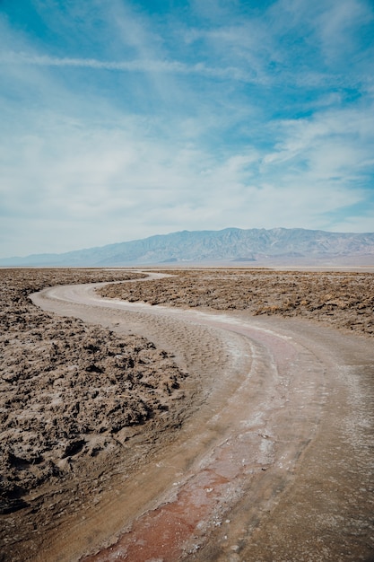 Vertical shot of a winding road surrounded by a sandy ground