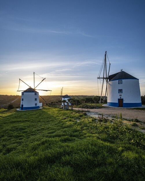 Vertical shot of windmills with a sunrise in a clear blue sky in the background