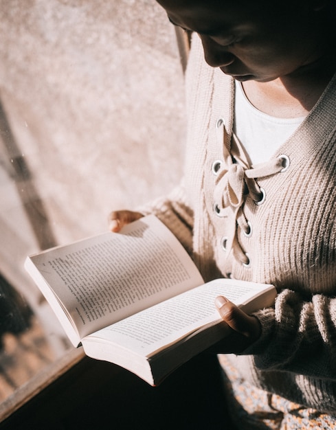 Foto gratuita ripresa verticale di una donna che legge un libro