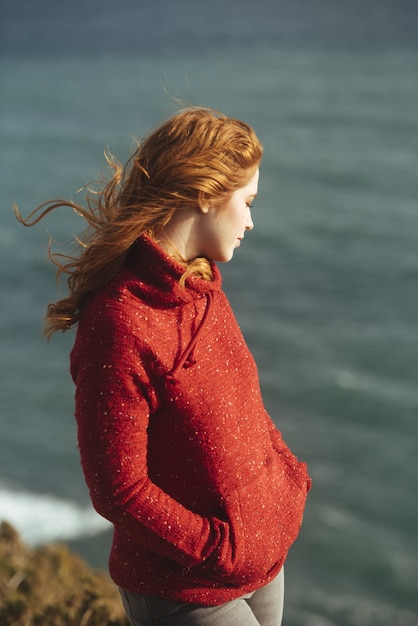 Foto gratuita colpo verticale di una donna in piedi sulla riva con il mare