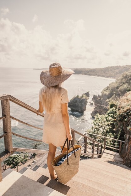 해변 옆에 핸드백을 들고 계단을 내려가는 여자의 세로 샷