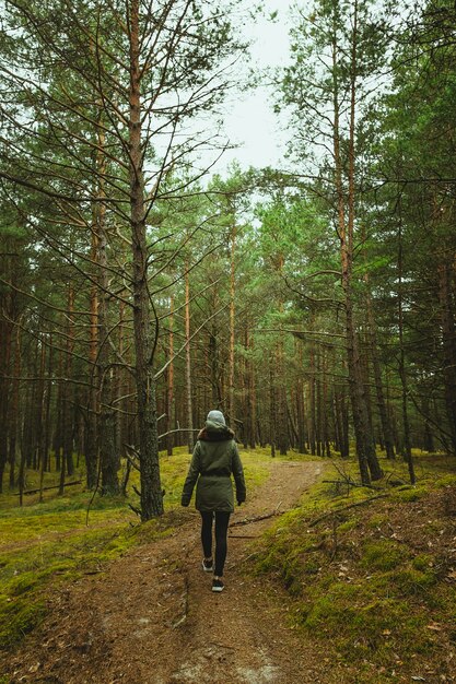 Vertical shot of a woman walking through the forest