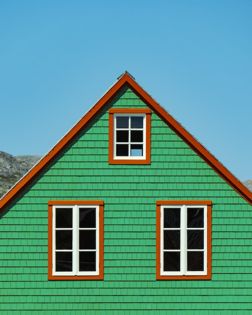 Вертикальная съемка деревянного зеленого дома под ясным голубым небом