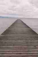 Free photo vertical shot of a wooden pier over the calm ocean under the beautiful cloudy sky