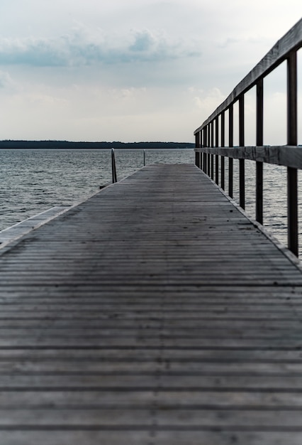 Vertical shot of a wooden pier at the cpast of the beautiful see under a cloudy sky