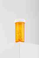 Free photo vertical shot of a yellow container filled with pills on a white table