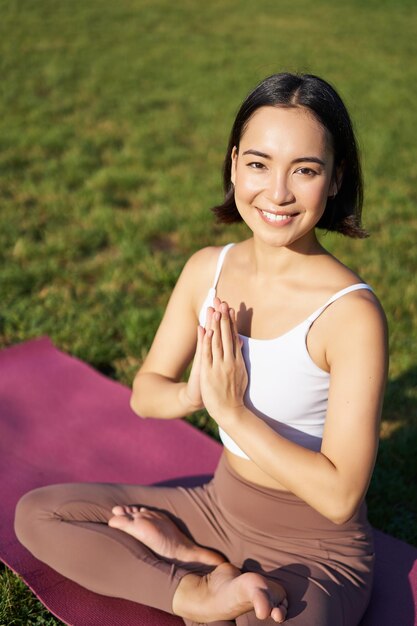 Vertical shot of young asian woman doing yoga practice mindfulness smiling and looking relaxed sitti