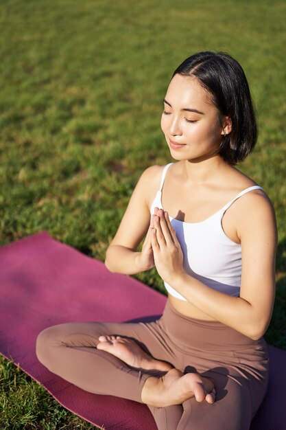 Vertical shot of young asian woman doing yoga practice mindfulness smiling and looking relaxed sitti