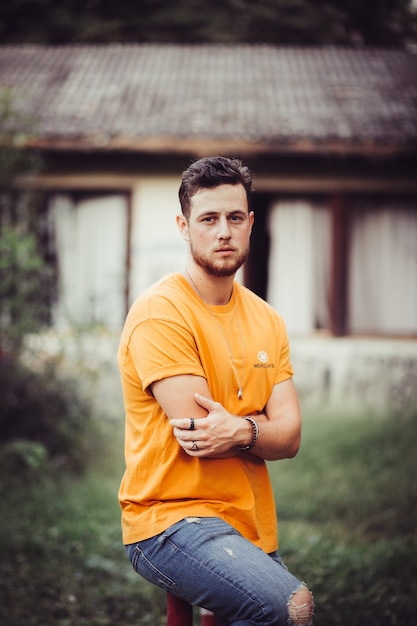 Free photo vertical shot of a young caucasian man with blonde hair wearing an orange shirt