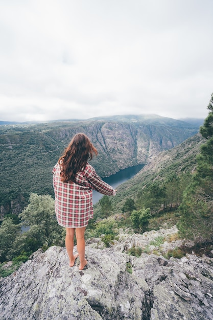 Vertical shot of a young Caucasian woman in Sil Canyon in Spain