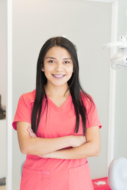 Вертикальный снимок молодой женщины-стоматолога в ее кабинете, предлагающей различные виды стоматологических услуг