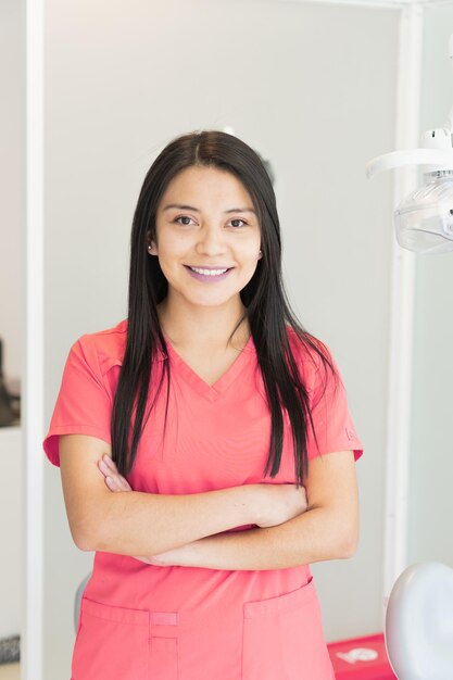 Вертикальный снимок молодой женщины-стоматолога в ее кабинете, предлагающей различные виды стоматологических услуг