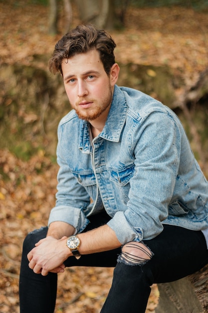 Free photo vertical shot of a young handsome guy in an autumn park