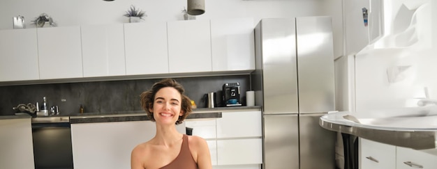 Vertical shot of young smiling woman healthy and fit girl doing yoga at home meditating in bright