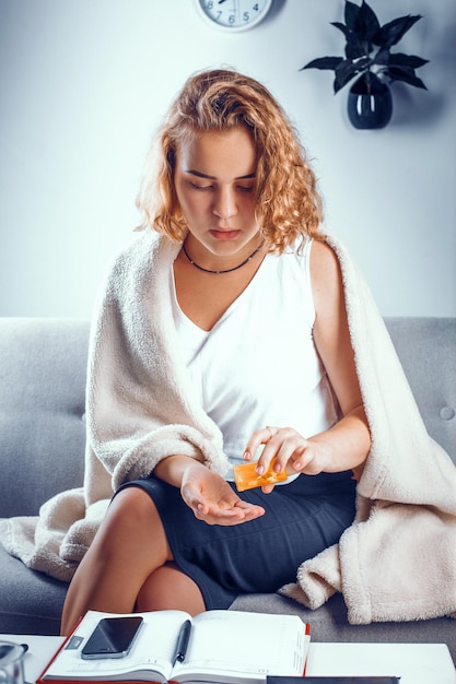 Free photo vertical shot of a young student pouring some pills from the orange bottle onto her palm