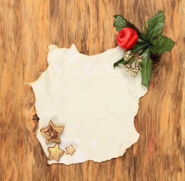 Free photo vertical top view shot of a burnt paper with christmas ornaments on a wooden surface