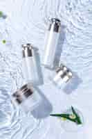 Free photo vertical top view of skincare bottles on a white water surface