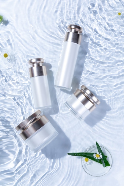 Vertical top view of skincare bottles on a white water surface