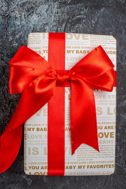 Vertical view of beautiful gift box tied with red ribbon on icy dark background