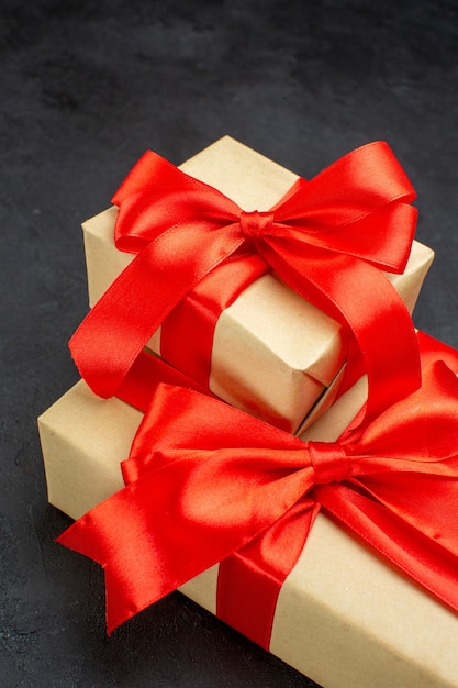 Vertical view of beautiful gifts with red ribbon on dark background