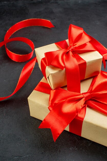 Vertical view of beautiful gifts with red ribbon on dark background