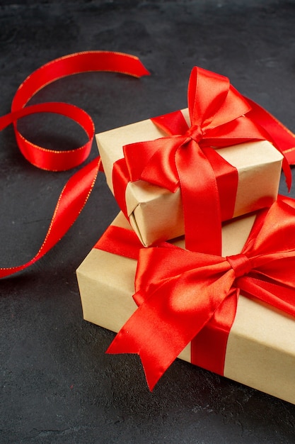 Vertical view of beautiful gifts with red ribbon on dark background