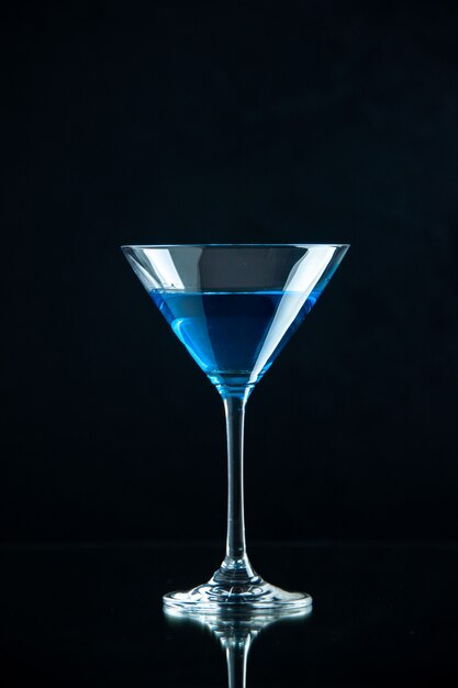 Вертикальный вид голубой воды в стеклянном кубке на темном фоне