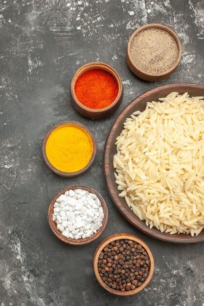 Vertical view of boiled rice in a brown wooden pot and different spices