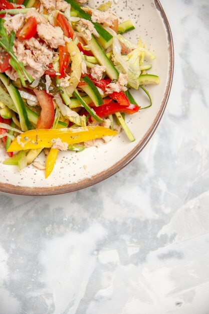 Vertical view of chicken salad with vegetables on stained white surface