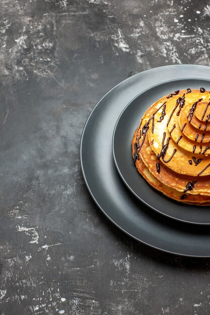 Vertical view of chocolate lovers delicious pancake on black plate and gray