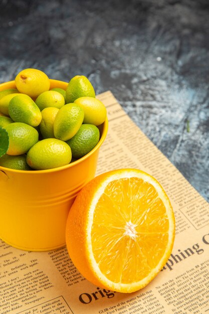 Vertical view of citrus fruits on newspaper on gray background