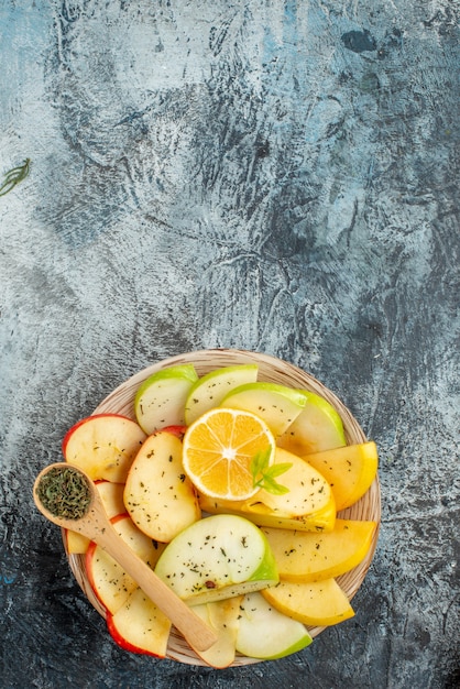 Vertical view of collection of fresh natural organic apple slices on a white plate on the bottom on a dark background