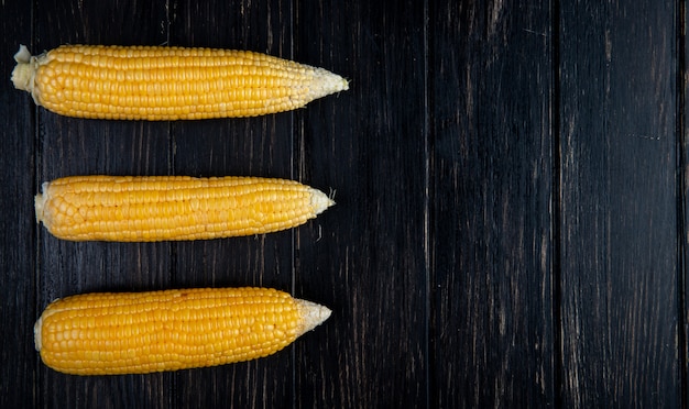 Vertical view of cooked corns on left side and black table 