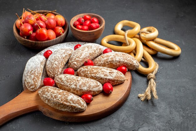 Vertical view of delicious banana cookies with fruits in bowls on black table