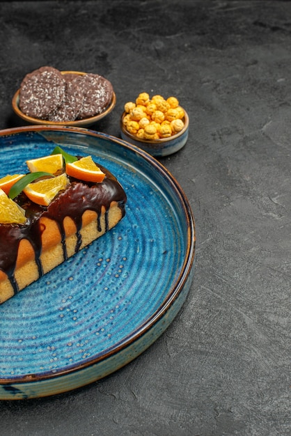 Vertical view of delicious cakes on blue tray and biscuits on dark background