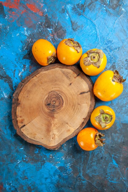 Vertical view of delicious fresh natural diospyros kaki and brown wooden cutting board