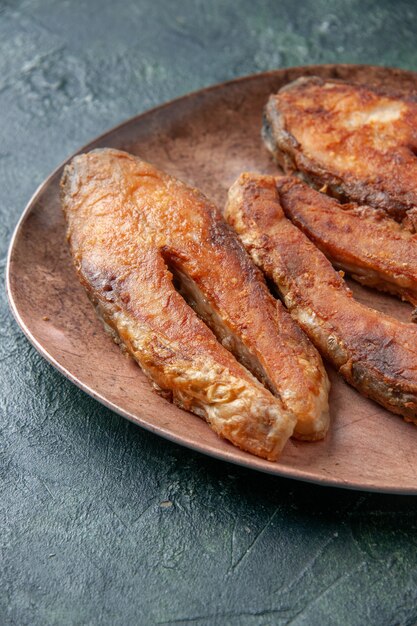 Vertical view of delicious fried fish on a brown plate on mix colors table with free space