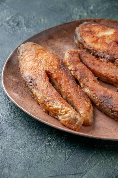 여유 공간이있는 혼합 색상 테이블에 갈색 접시에 맛있는 튀긴 생선의 세로보기