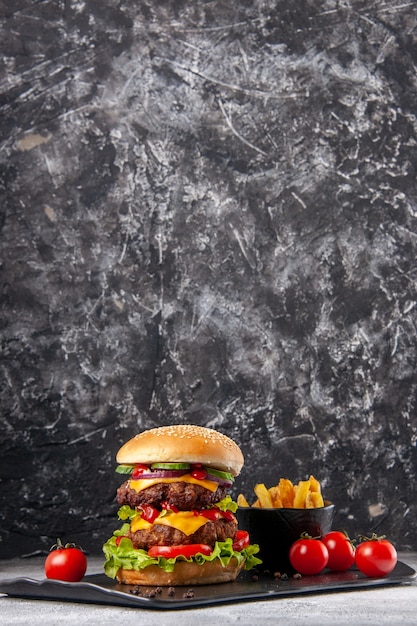 Free photo vertical view of delicious homemade sandwich and fries ketchup on black board on gray ice surface