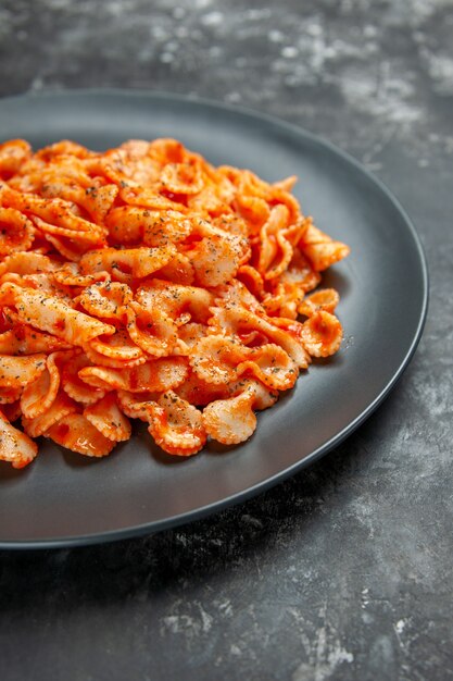 Vertical view of delicious pasta meal on a black plate for dinner on dark background