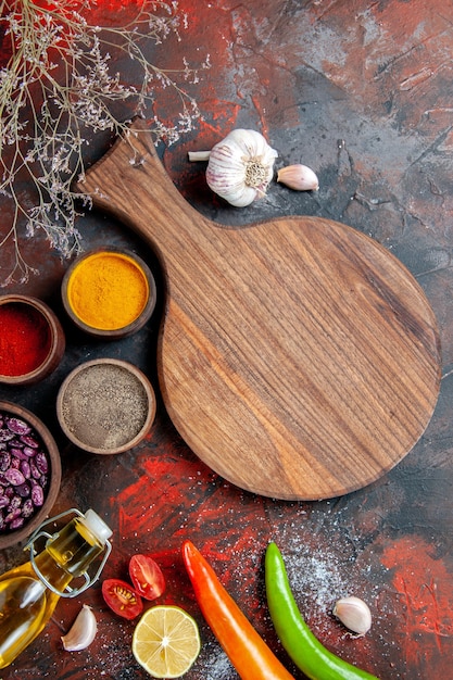 Vertical view of dinner background fallen oil bottle beans cutting board and different spices