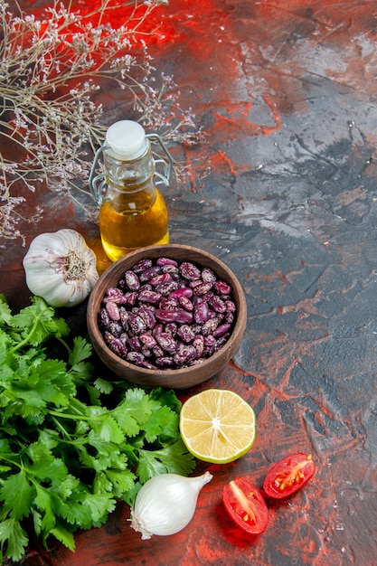 Vista verticale della preparazione della cena con cibi e fagioli bottiglia di olio e un mazzo di limone verde pomodoro sulla tabella di colore misto